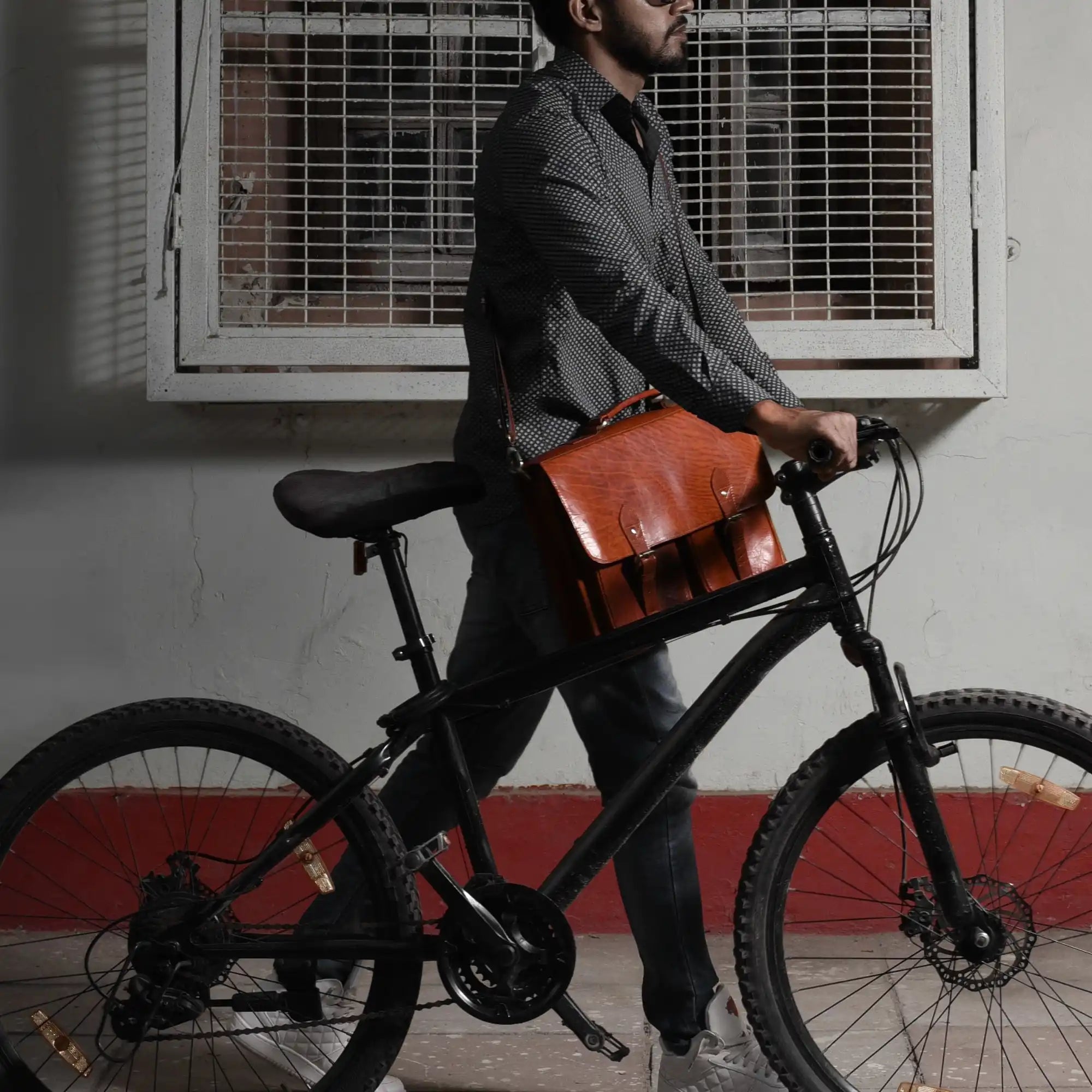 Man with bicycle and leather satchel.